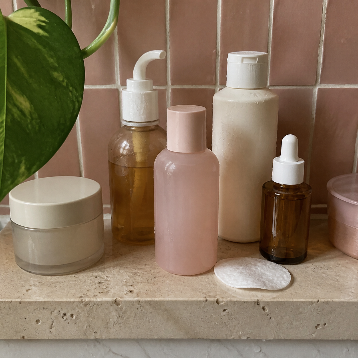Skincare shelf with blush tile and a trailing plant leaf